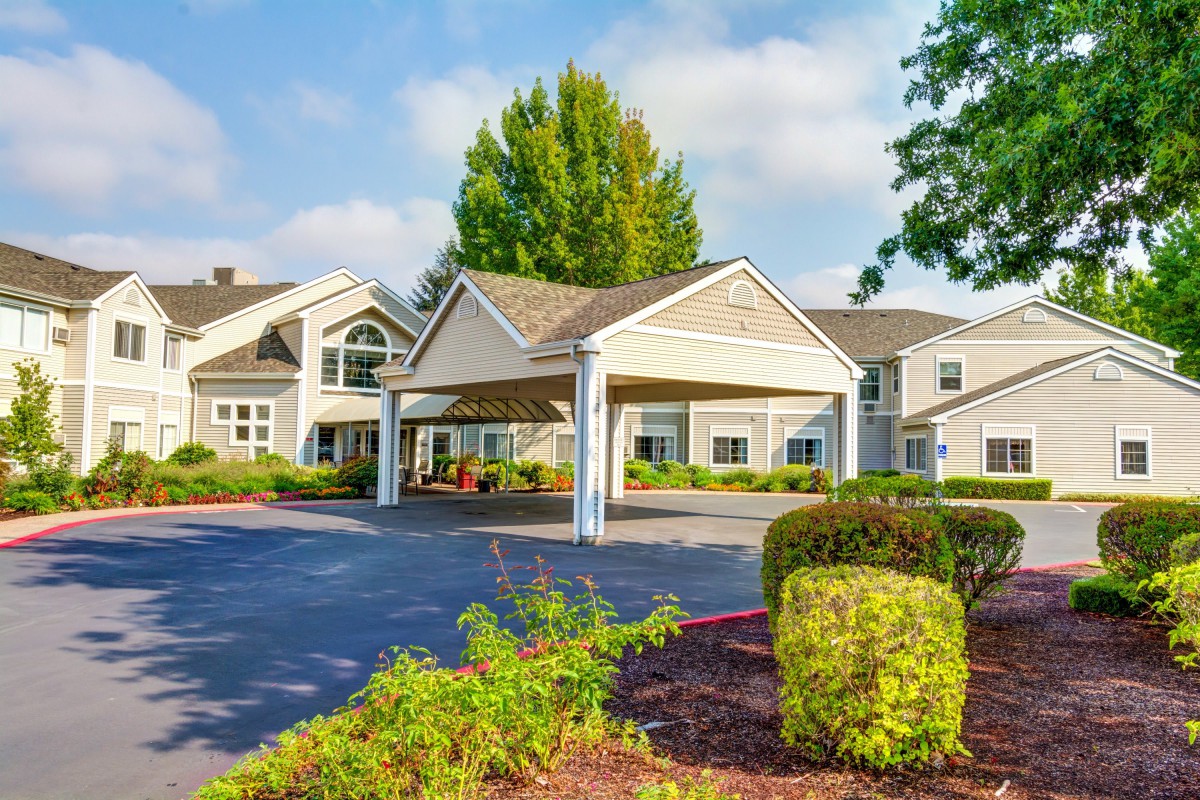 A residential building with a driveway and landscaped entrance.