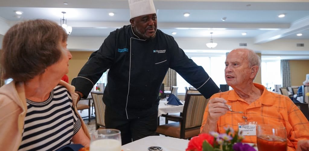 A chef engaging with diners at a restaurant.