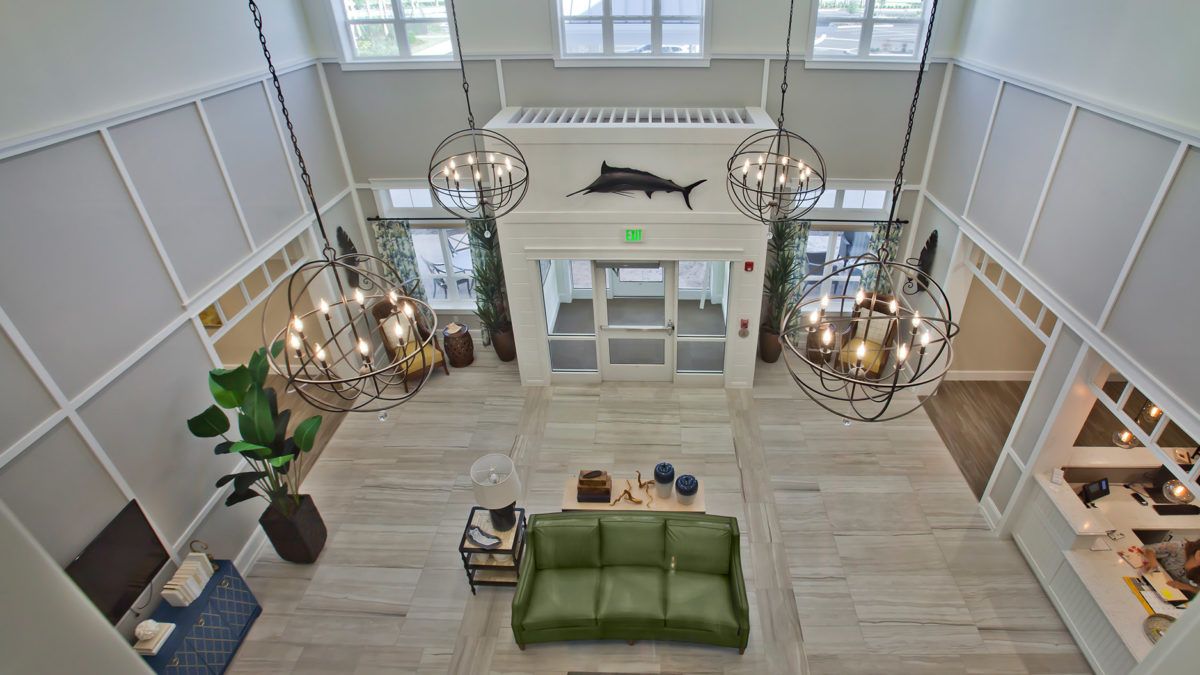 Aerial view of a spacious lobby featuring modern decor, chandeliers, and a green sofa.