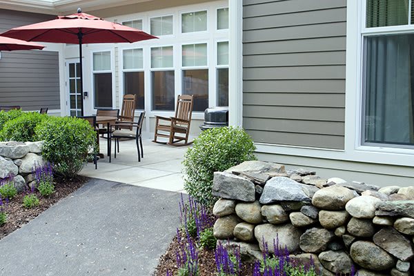 A cozy outdoor patio with a dining set, umbrella, and well-maintained garden.