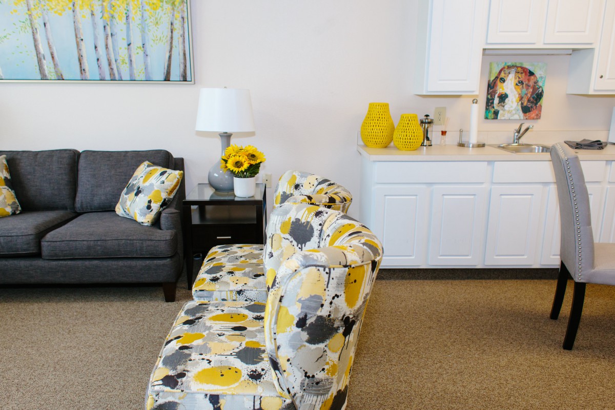 A modern living room with floral-patterned furniture and vibrant yellow accents.