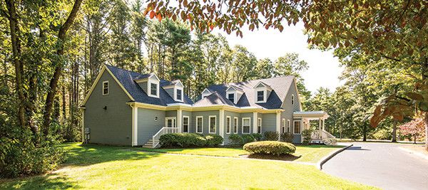 A charming residential house surrounded by a lush lawn and trees, illuminated by daylight.