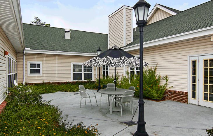 A cozy outdoor patio area with a table, chairs, and an umbrella next to a building.
