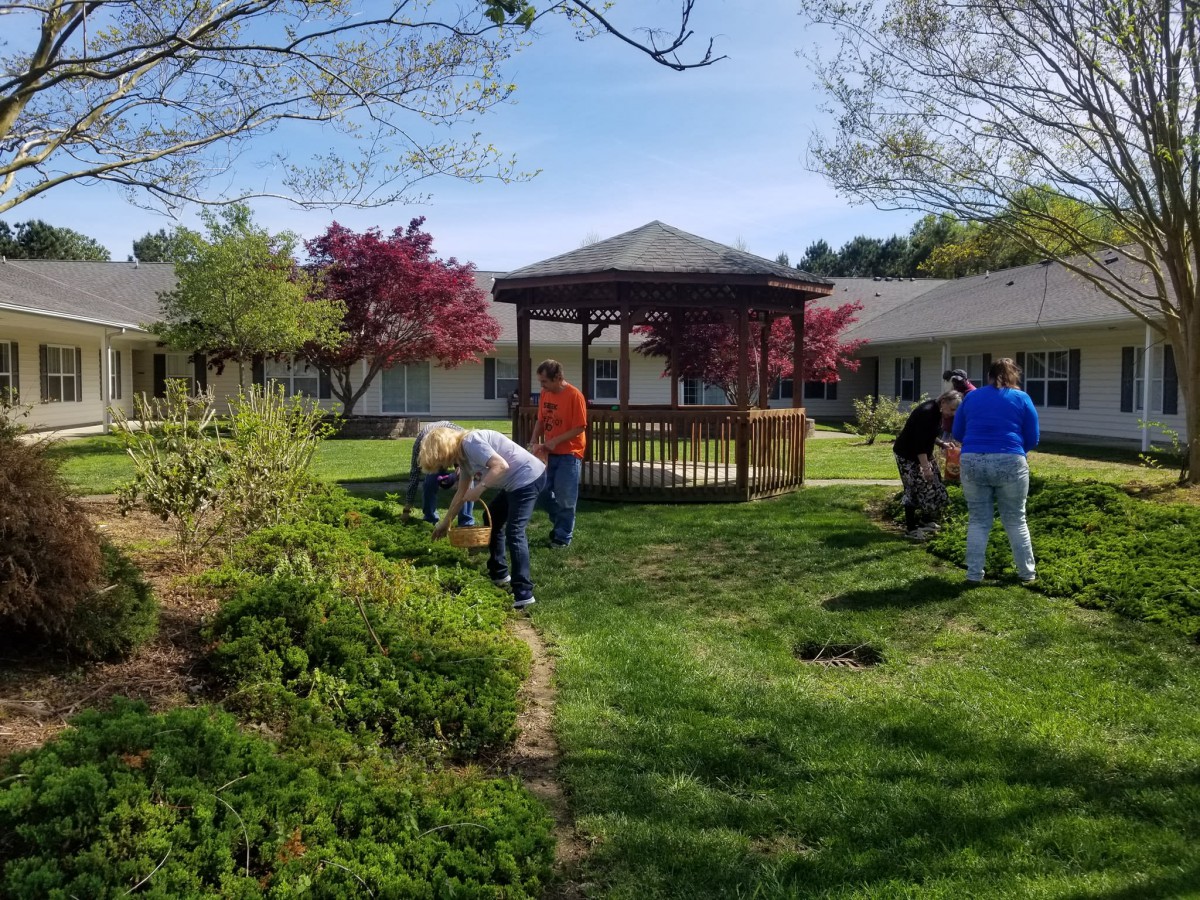 A group of people gardening near a gazebo in a park setting.