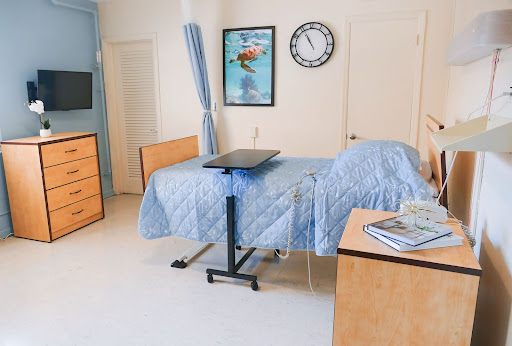 A well-organized and clean hospital patient room featuring a bed, medical equipment, and decorative artwork.