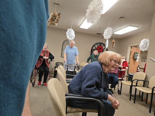 An engaged social gathering of elderly individuals at a community center, decorated for the holidays.