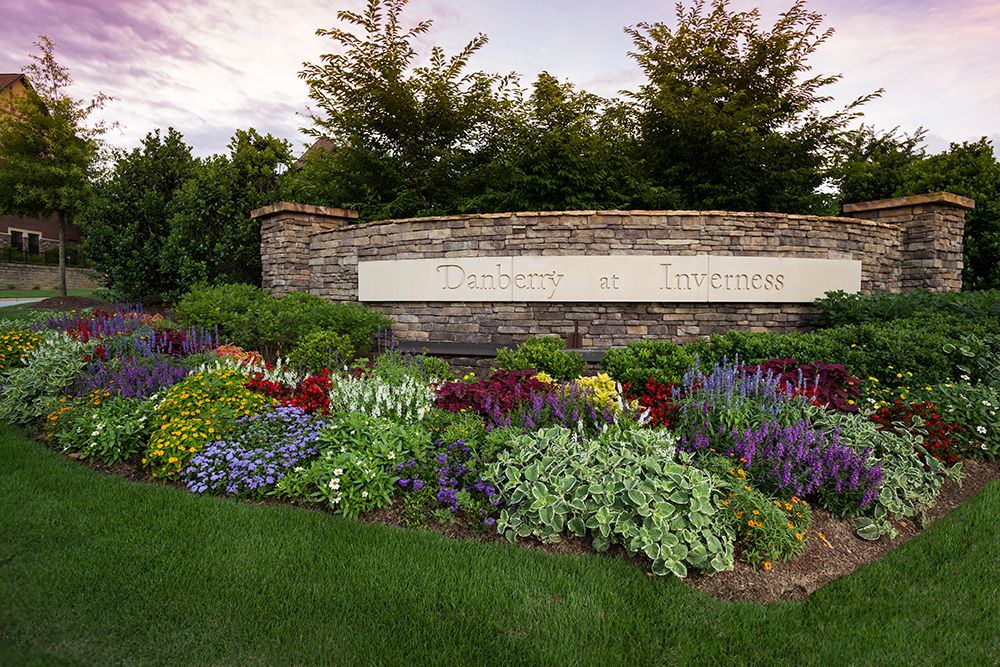 A beautifully landscaped garden with vibrant flowers in front of a stone wall.