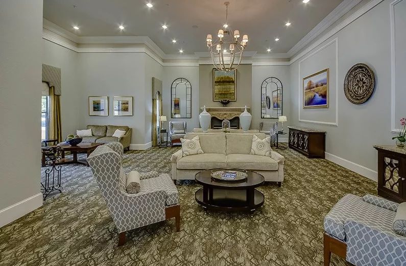 A spacious and elegantly decorated living room featuring a chandelier, comfortable seating, and tasteful decor.