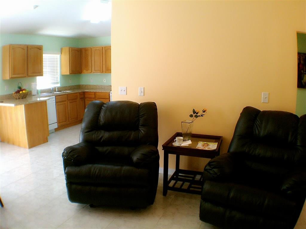 A cozy living room with recliner chairs and a view into the kitchen area.