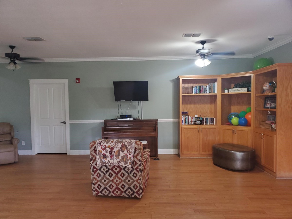 A cozy living room with a TV, bookshelf, and armchair.
