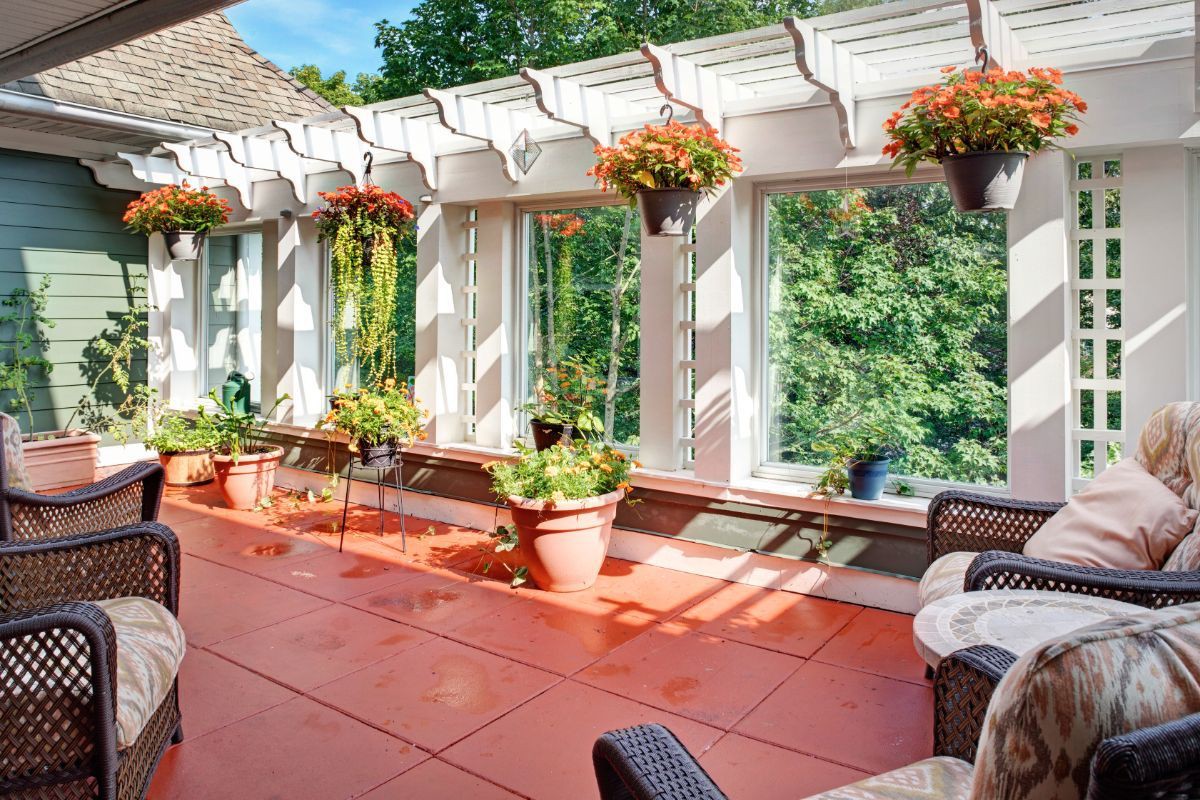 A sunny patio with a pergola adorned with hanging plants and outdoor seating.