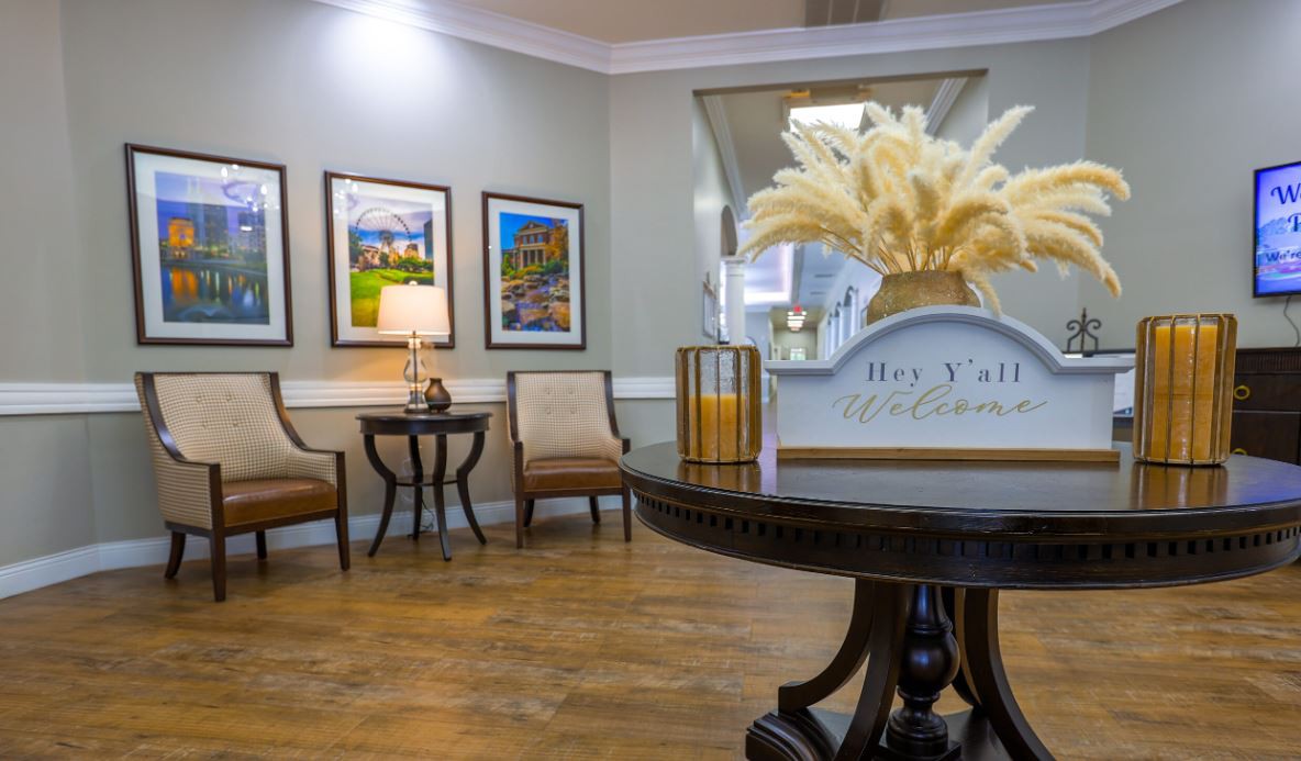 A cozy and elegantly decorated lobby area with seating, artwork on the walls, and a central table adorned with a decorative piece.