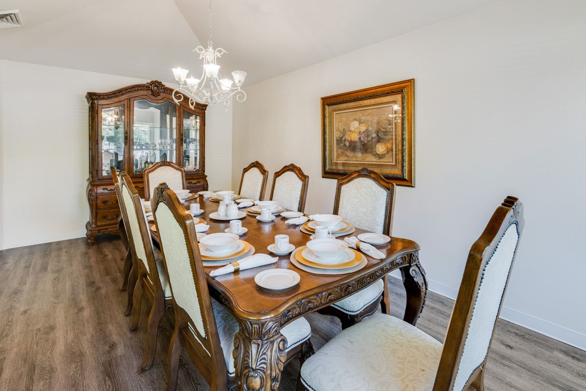 A beautifully set dining room with elegant, traditional furniture and a classic chandelier.