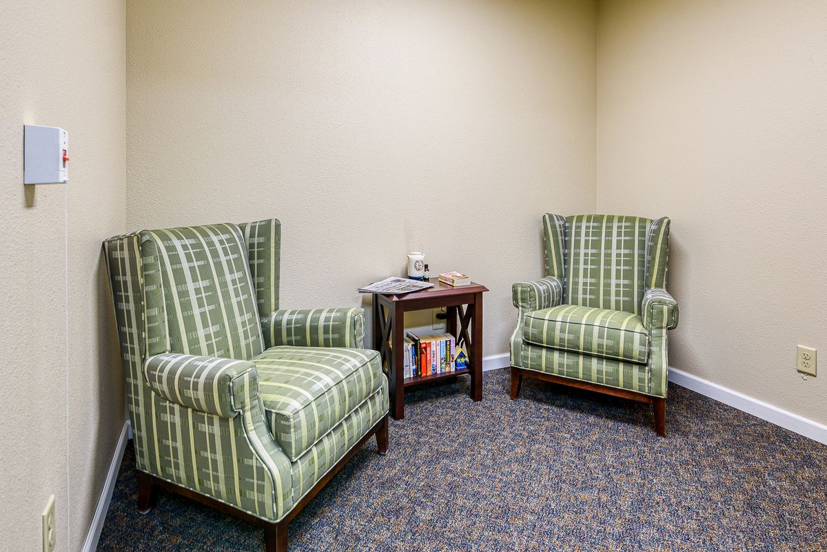 A cozy seating area with two patterned armchairs and a small table with magazines.
