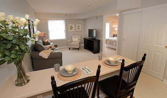 A cozy living room featuring a sofa, television, and a small dining area with table settings.