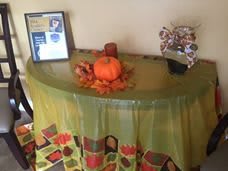 A table decorated for autumn with a pumpkin centerpiece and fall leaves.