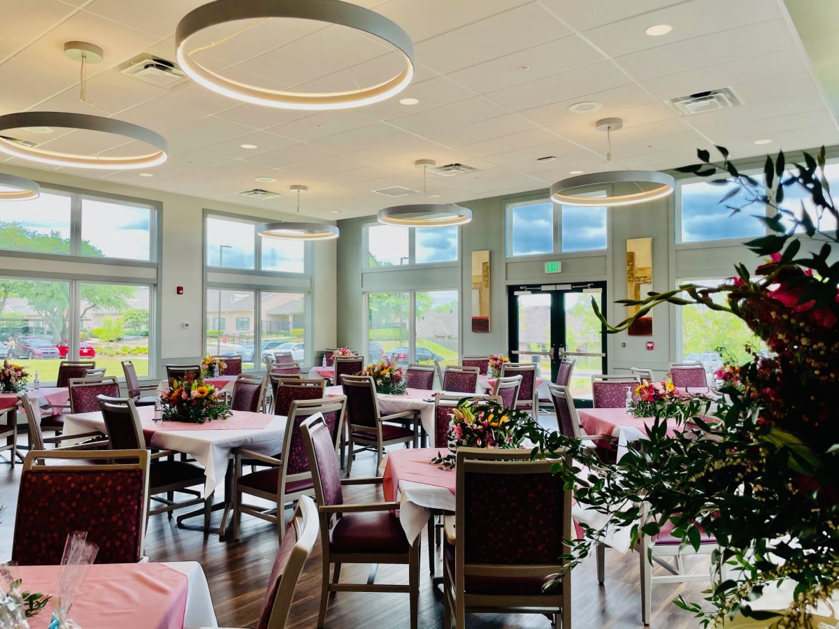 A spacious restaurant dining area with large windows and neatly arranged tables.