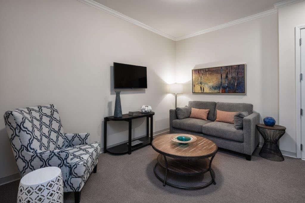 A modern living room with a gray sofa, round coffee table, and wall art.