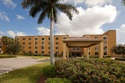 A welcoming hotel entrance surrounded by lush landscaping and palm trees.