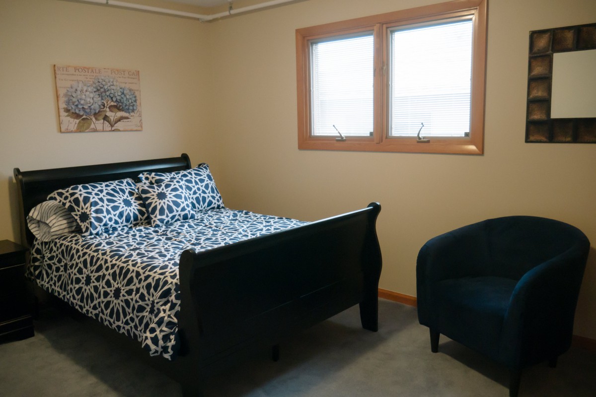 A cozy bedroom with a patterned bed set and armchair.