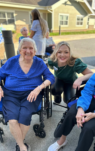 A joyful moment shared between an elderly woman and her caregiver smiles in the sunshine.