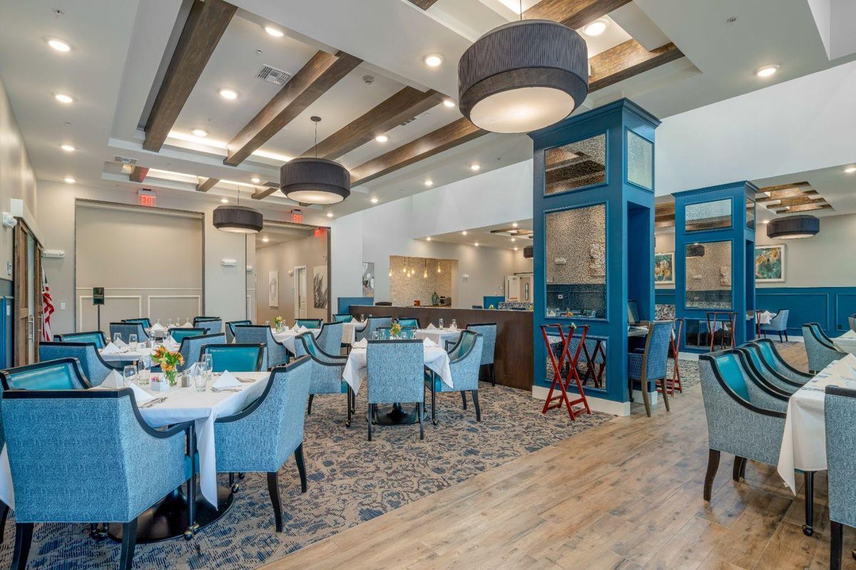 A modern restaurant interior with elegant tables and chairs, featuring stylish lighting and decor.