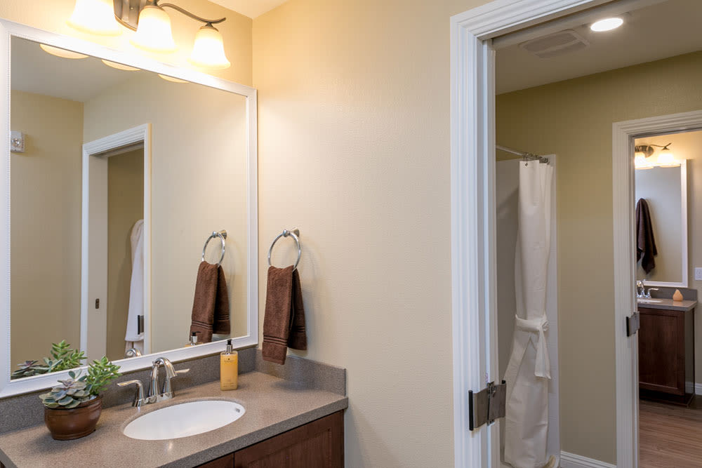 A clean and modern bathroom with a large mirror, sink, and towels.