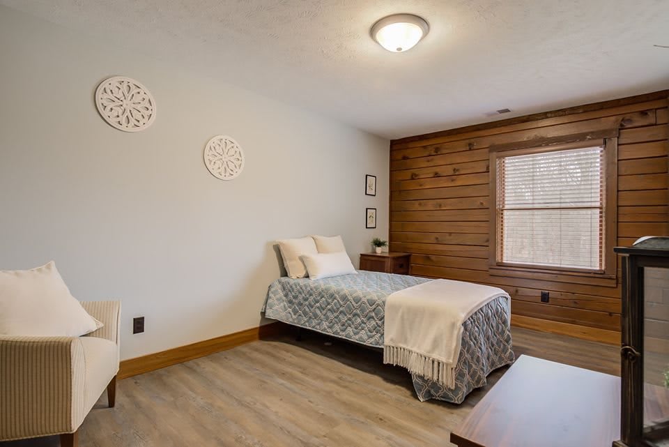 A minimalist bedroom featuring a single bed with wood paneling and neutral decor.