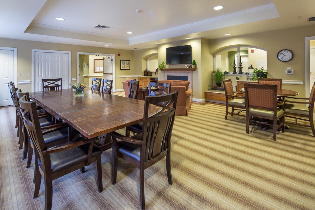 A cozy dining area with wooden tables and chairs, featuring a television and fireplace.