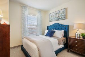 A cozy bedroom with a blue upholstered bed, decorative pillows, and wall art.