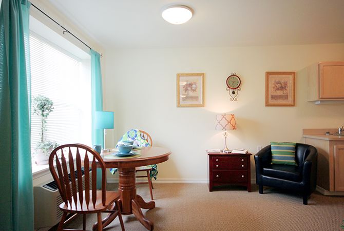 A cozy living room featuring a wooden table and chair, a striped sofa, and decorative lamps.