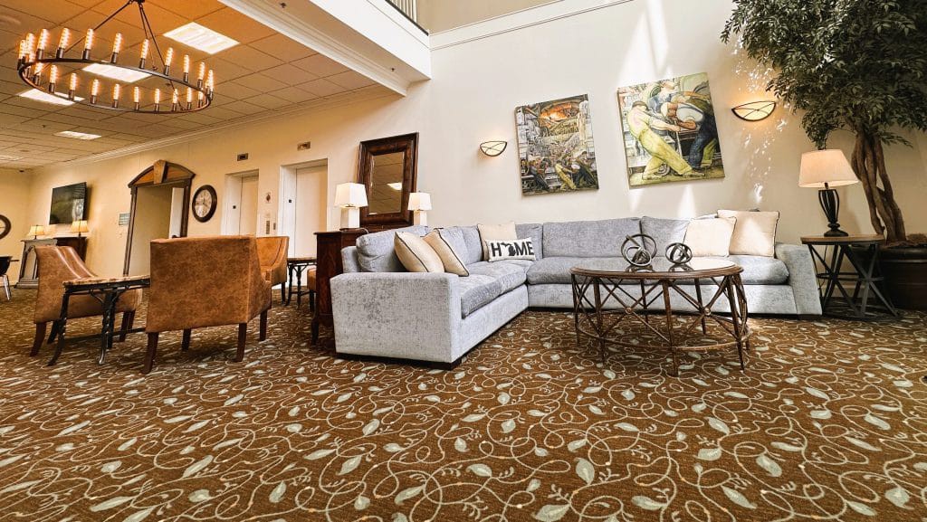 A spacious living room with a cozy sofa, patterned carpet, and decorative artwork on the walls.