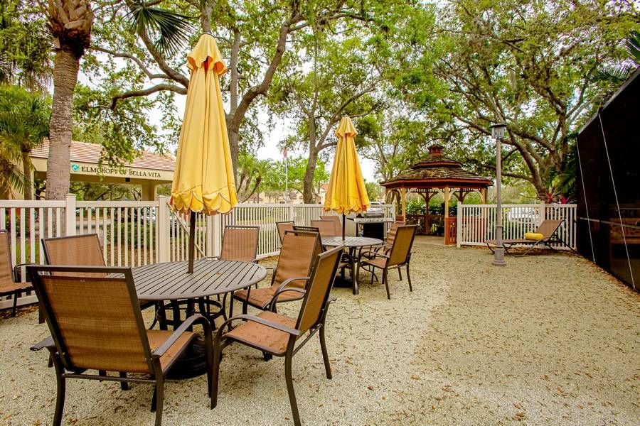 An inviting outdoor patio area with tables, chairs, and yellow umbrellas, surrounded by trees.