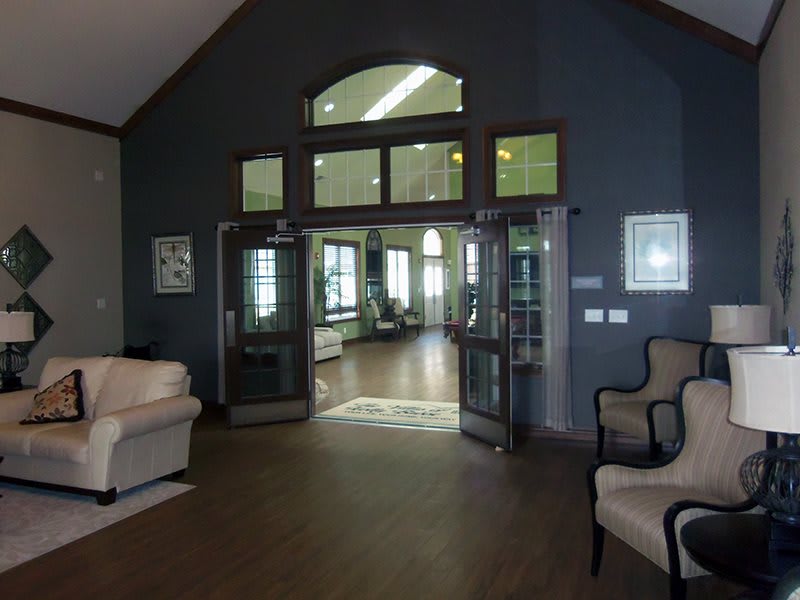 A modern living room interior with sofas and chairs arranged around an open doorway leading to another room.