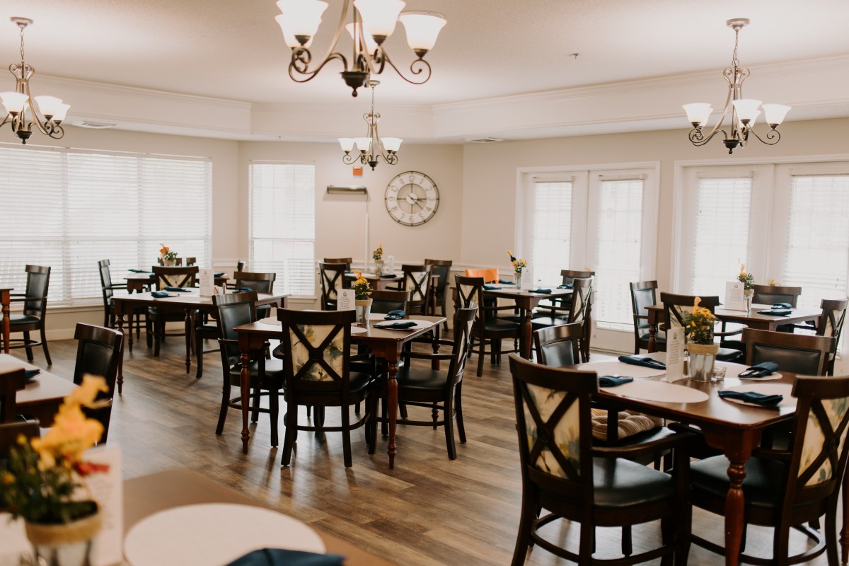 An elegantly decorated dining room featuring multiple tables and chairs set under a chandelier.