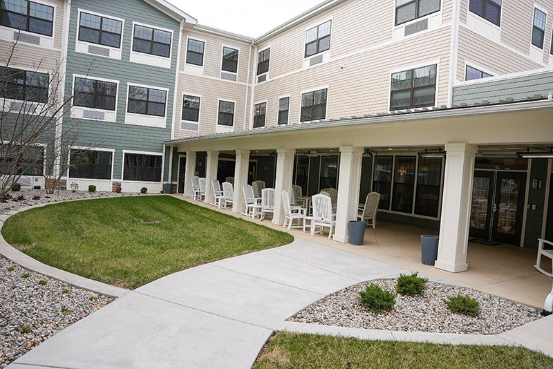A modern residential building with a covered patio area and landscaped garden.