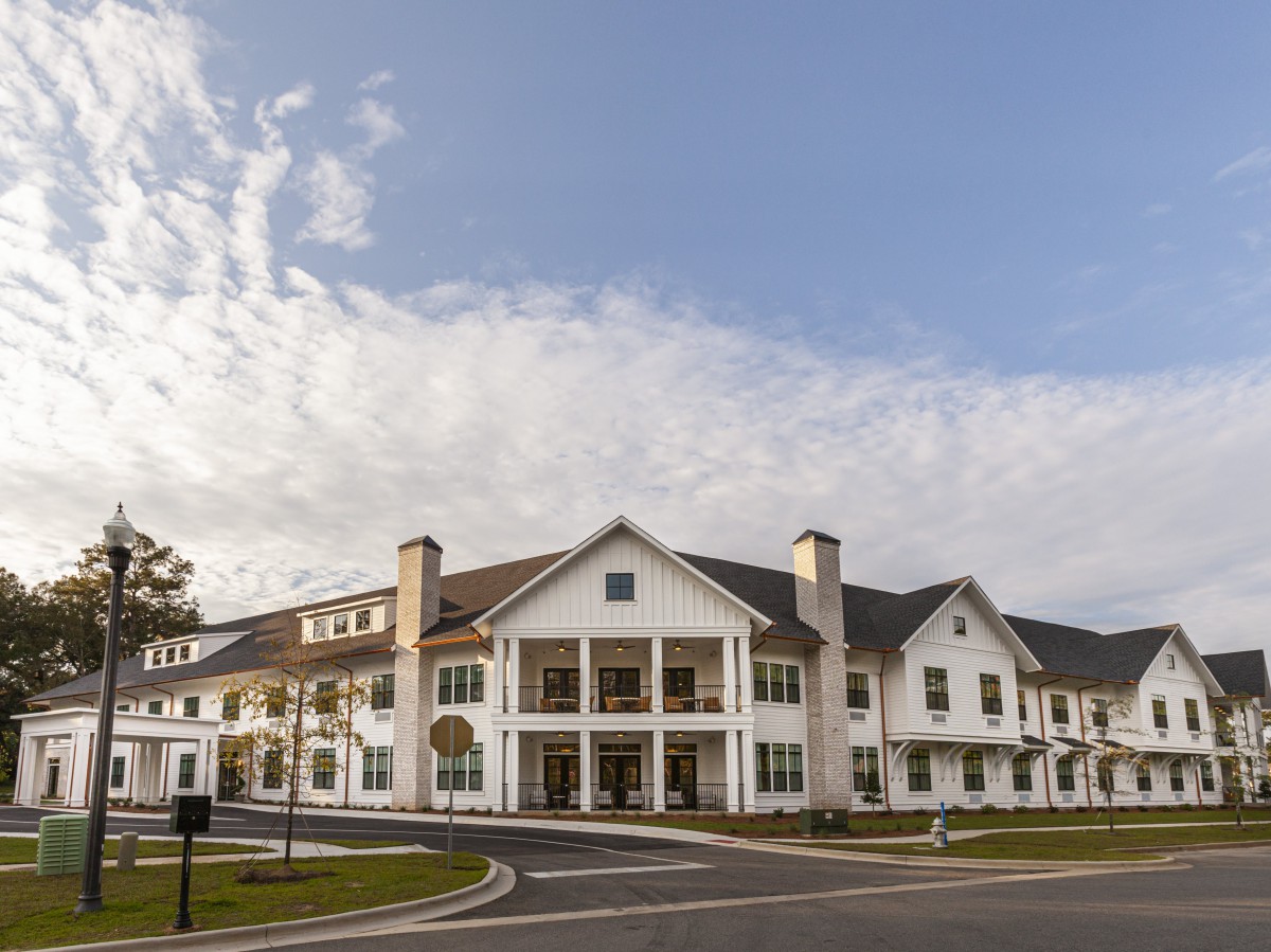 Elegant residential building with a spacious driveway under a cloudy sky.