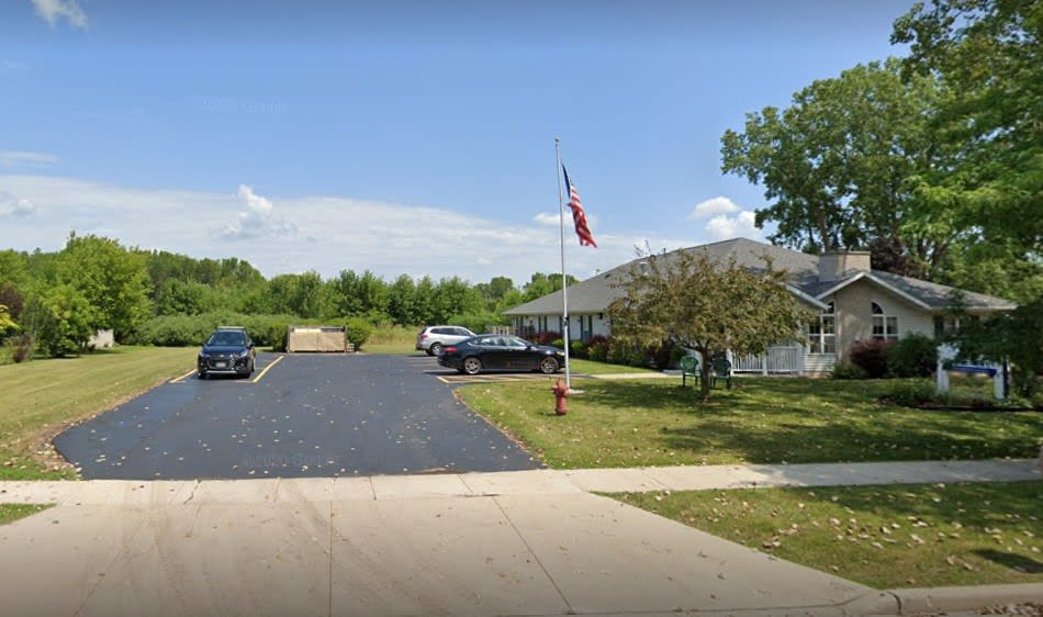A single-story building with a parking lot, several cars, and a flagpole in front.