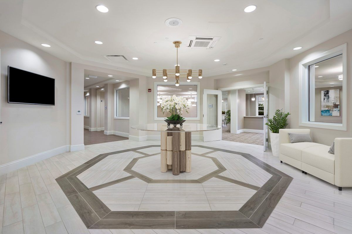 A modern, elegantly designed lobby featuring a chandelier and central floral arrangement.