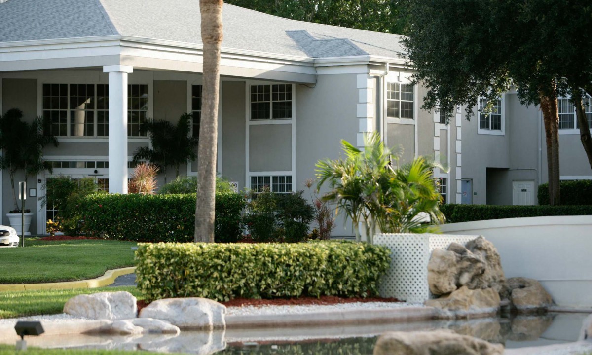A well-maintained residential home with a garden and palm trees in front.