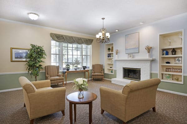 A cozy living room with a fireplace, comfortable seating, and large windows.
