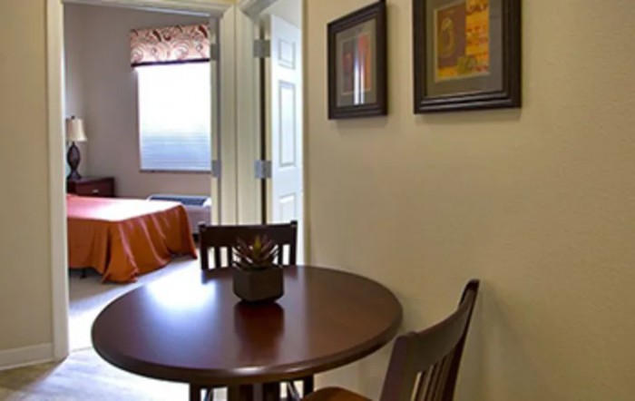 A cozy dining area with a round table and chairs next to a bedroom.