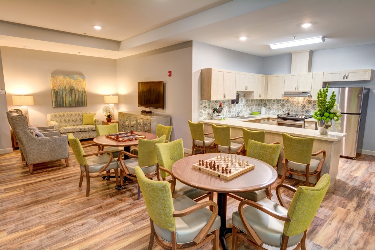 A cozy lounge area with tables, chairs, and a kitchenette, featuring chessboards for entertainment.