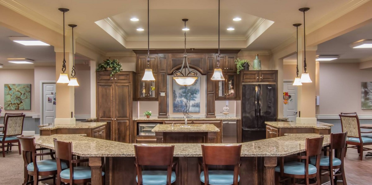 A modern kitchen with wooden cabinets, stylish lighting fixtures, and a central island with seating.