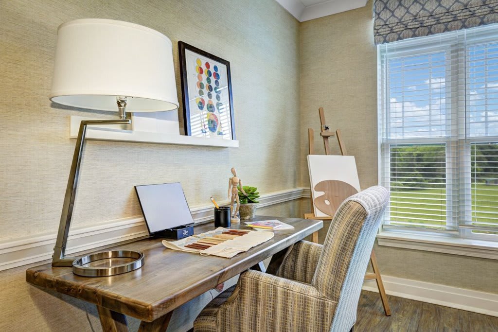 A cozy home office with a wooden desk, laptop, and decorative artwork.