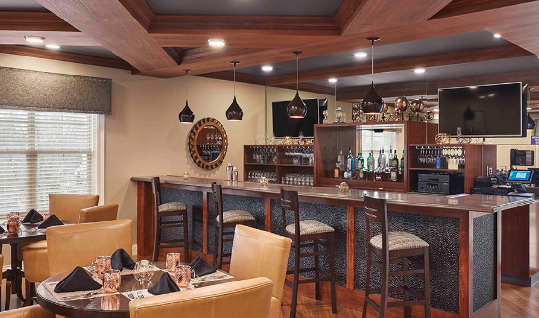 A cozy bar interior with seating and modern lighting.