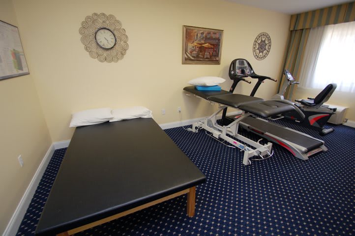 A therapy room with massage tables, exercise equipment, and wall decorations.