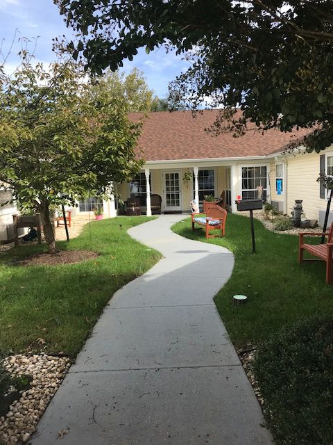 A quaint house with a winding pathway surrounded by a well-maintained lawn and garden.