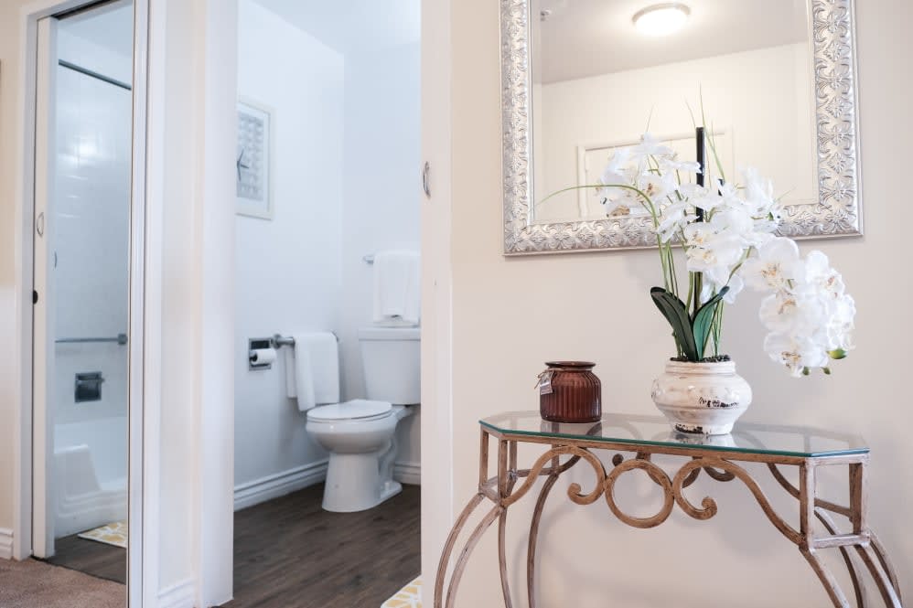 A stylish bathroom with elegant decor, featuring a white toilet and a decorative table with a plant.