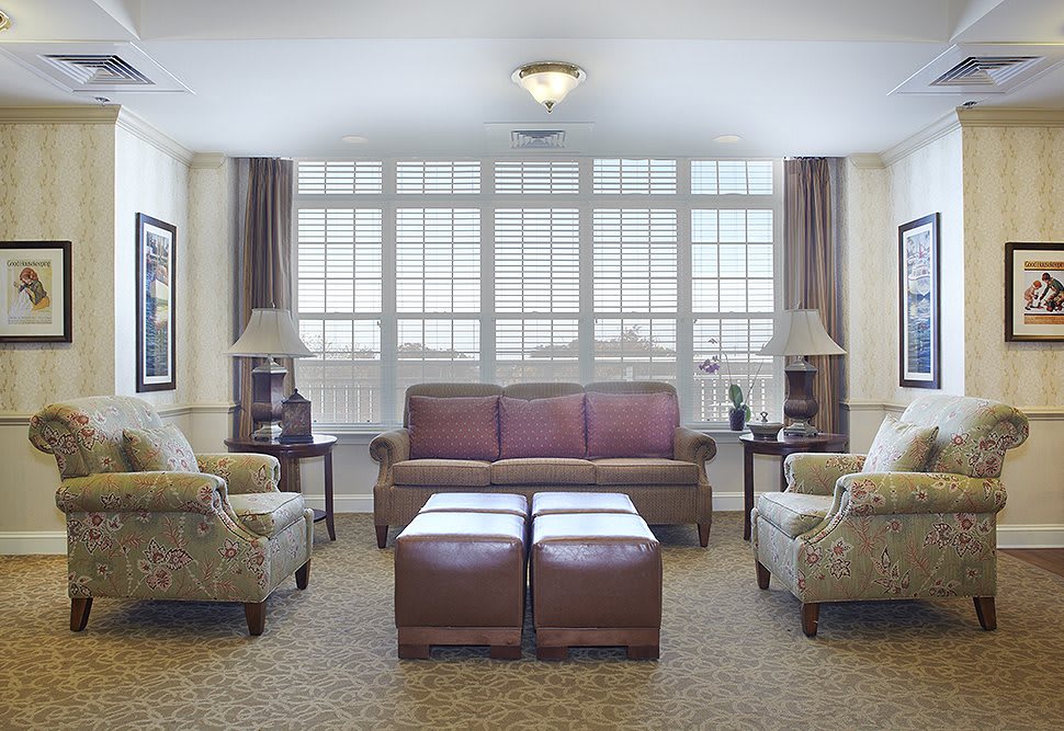 A cozy living room with a large sofa, armchairs, and coffee tables in front of a window.